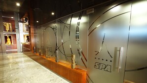 Un espace d’accueil doté d’un sol en marbre, d’un comptoir de réception en bois et de panneaux en verre dépoli ornés du mot « SPA » et d’éléments décoratifs.