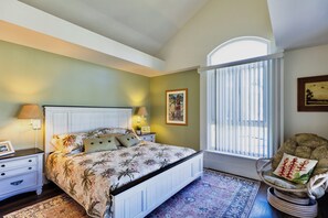 A bedroom with a bed, nightstands, a chair, and a window with blinds.