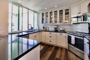 Una cucina moderna con un'isola grande, mobili bianchi ed elettrodomestici in acciaio inossidabile.