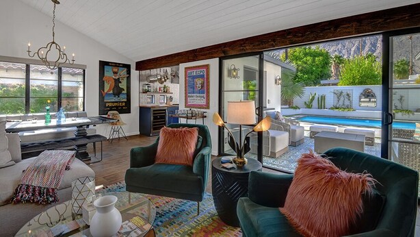 Un salon moderne avec vue sur la piscine, un coin repas et une cuisine.