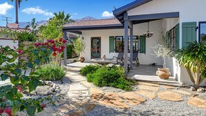 Une maison dotée d’un patio, d’un chemin en pierre et de diverses plantes.
