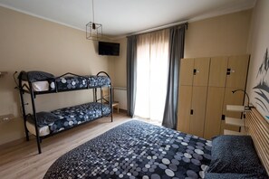 Una habitación tipo dormitorio con literas, televisión, radiador y ventana con cortinas.