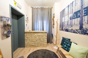Una habitación con un muro de acento de piedra, un banco de madera, una alfombra gris y un cartel grande con temática de bosque.
