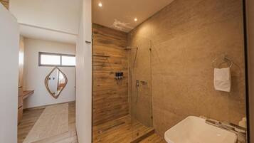 Un baño moderno con ducha de vidrio, una bañera blanca y piso de madera.
