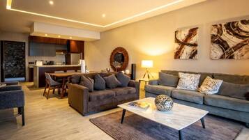 Un salon moderne comprenant un canapé, une table basse et un coin repas avec des chaises.