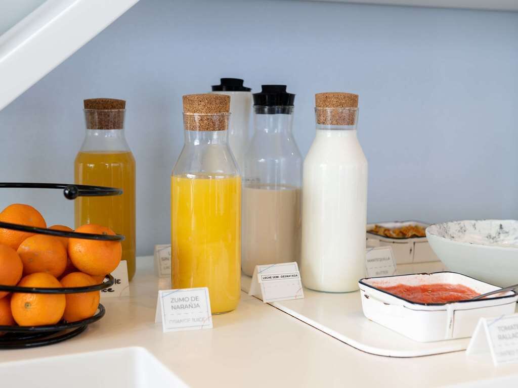 A breakfast buffet with various food items and beverages, including orange juice, milk, and a dish with tomato sauce.