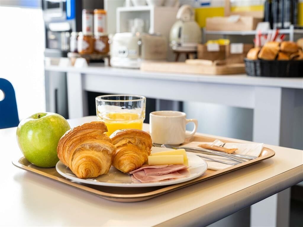 A breakfast tray with croissants, ham, cheese, an apple, and orange juice.