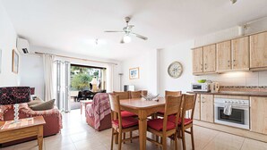 A spacious living area with a dining table, chairs, and a kitchen area with cabinets and appliances. - Jardines de Burriana 15 (Nerja)