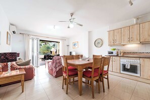 A spacious living area with a dining table, chairs, and a kitchen area with cabinets and appliances.
