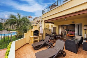 Eine Außenpatio mit Lounge-Möbeln, Grillbereich, Pool und Blick auf die umliegenden Gebäude.