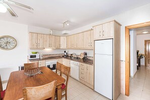 Une cuisine avec des meubles de rangement en bois, un four à micro-ondes, un évier et une table à manger avec des chaises.