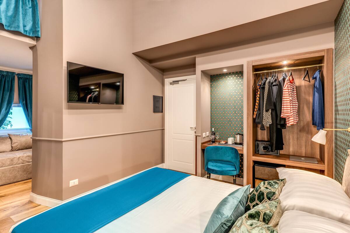 A bedroom with a bed, a desk, a chair, a wardrobe, and a mirror.