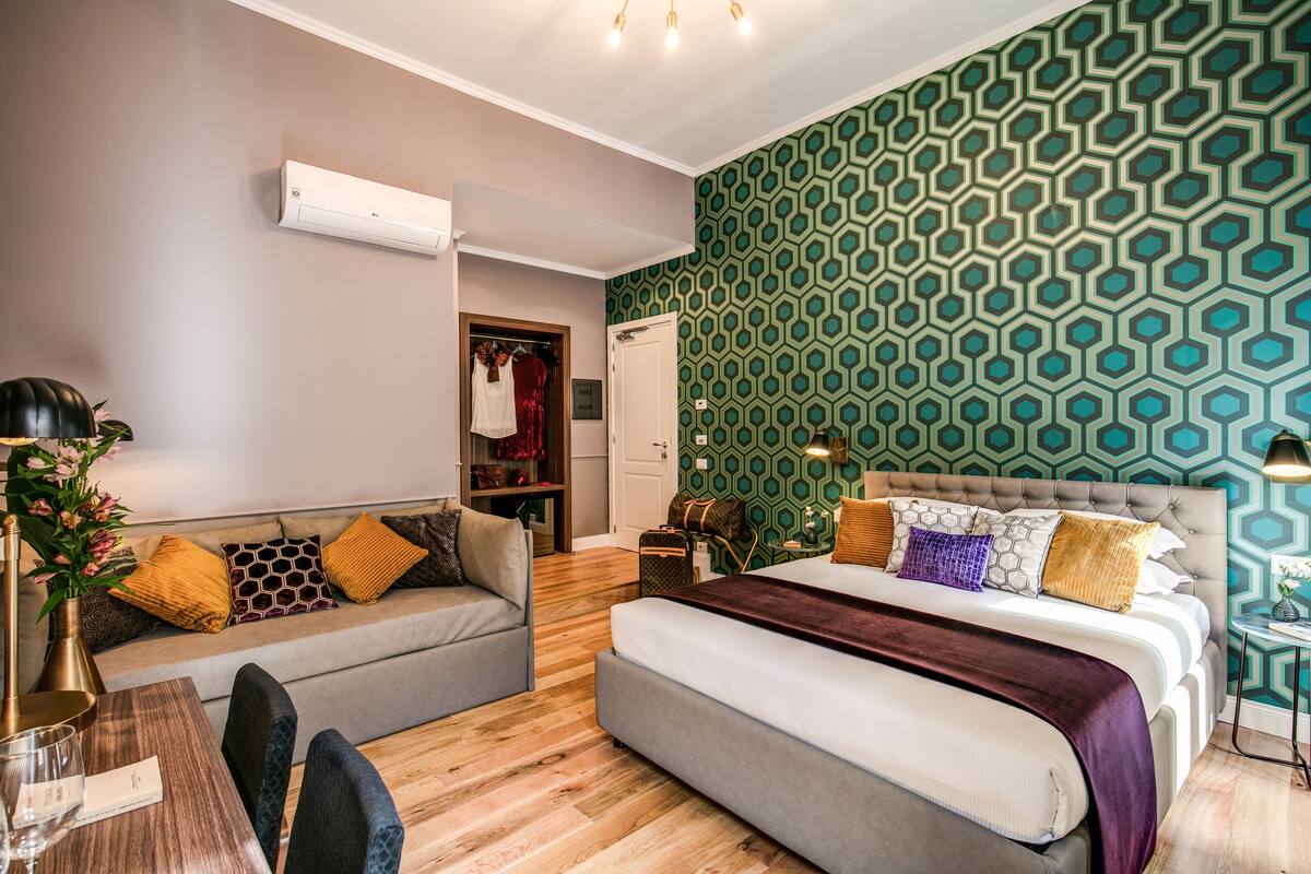 A modern bedroom with a bed, a sofa, a dining table, and a small side table.