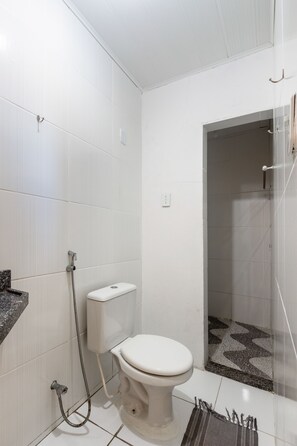 A small, white bathroom with a toilet, a shower, and a tiled floor. - OYO Pousada Cavalo Marinho (Baia da Traicao)