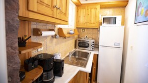 Eine kleine Küche mit Holzschränken, einer Mikrowelle, einem Toaster und einem Kühlschrank.