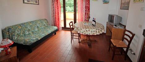 Una sala acogedora con sofá, una mesa de comedor con sillas, televisor y chimenea.