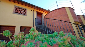 Un edificio con fachada amarilla, estructura de ladrillo y una escalera de metal que conduce a un balcón.