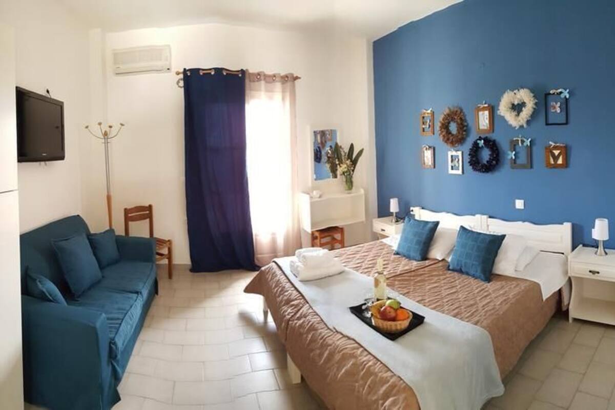 Un dormitorio con dos camas, una pared azul y un televisor en la pared.