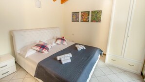 Um quarto com cama, almofadas, guarda-roupa e obras de arte na parede.