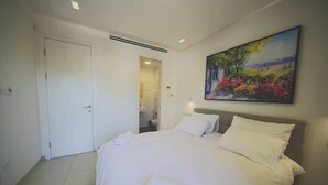 Ein Hotelzimmer mit einem großen Bett, einem Gemälde an der Wand und einer Tür zum Badezimmer.