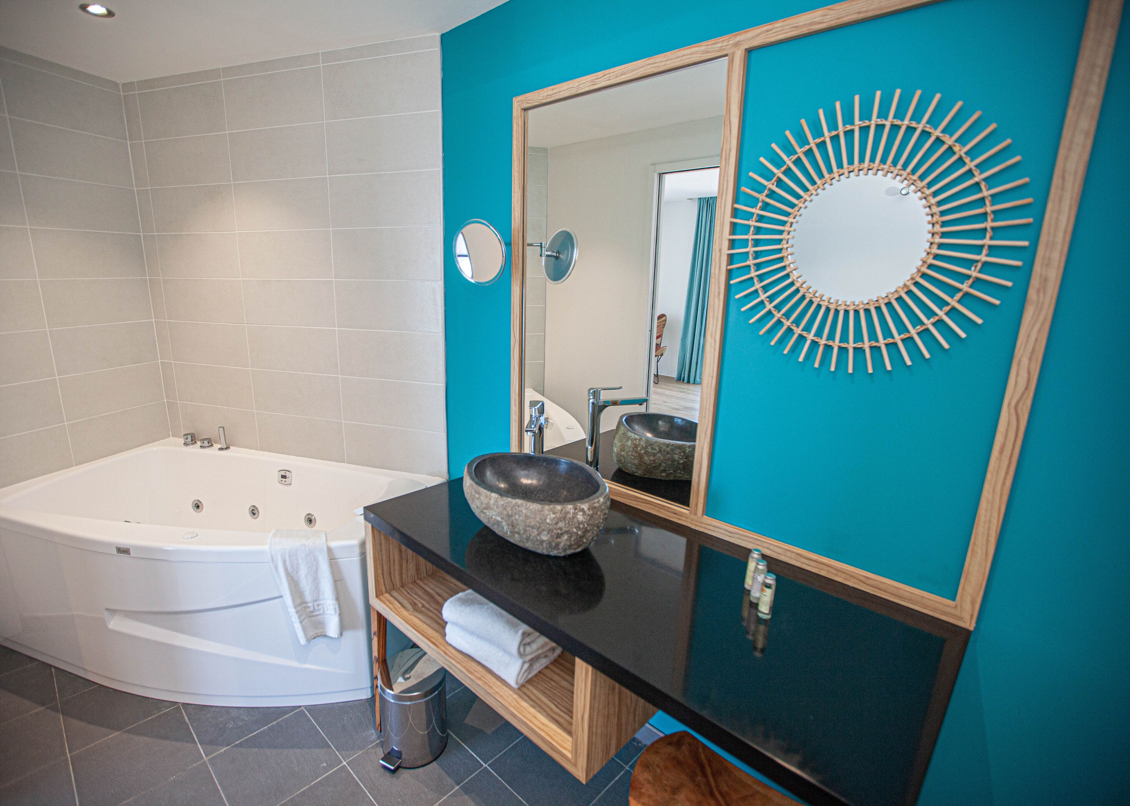 A modern bathroom with a freestanding bathtub, a round mirror, and a wooden vanity with a sink.