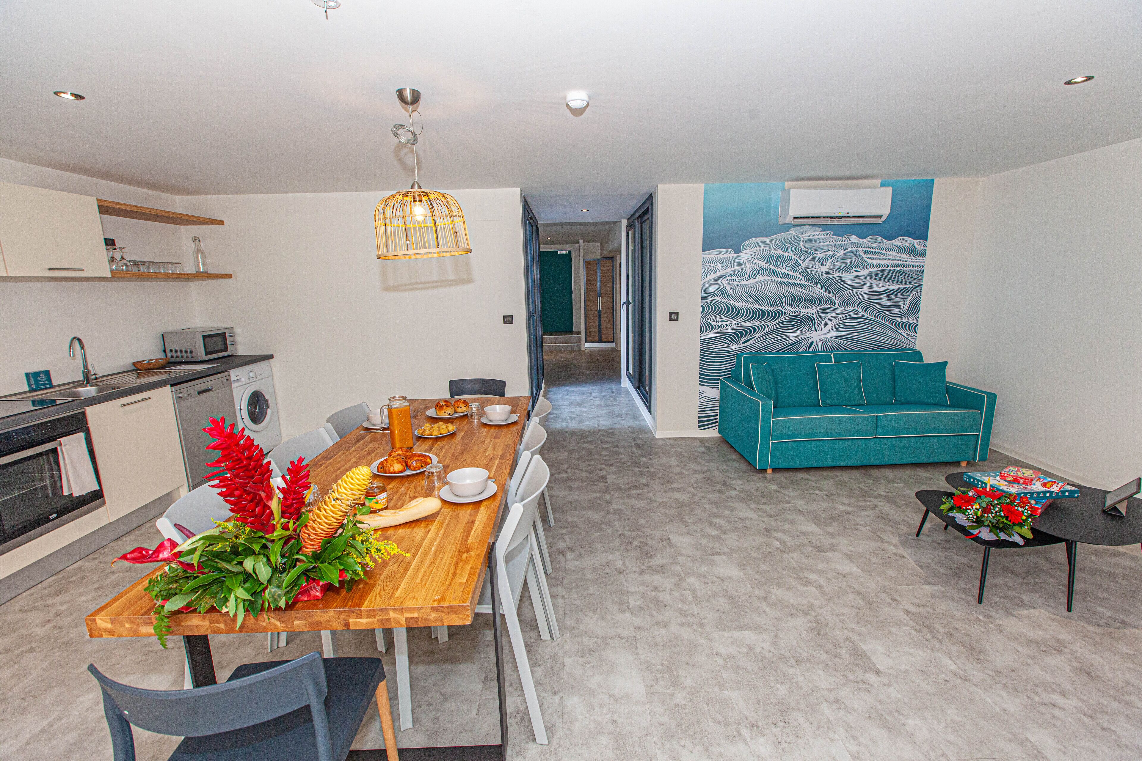 A modern kitchen with a wooden dining table, white chairs, and a built-in oven.