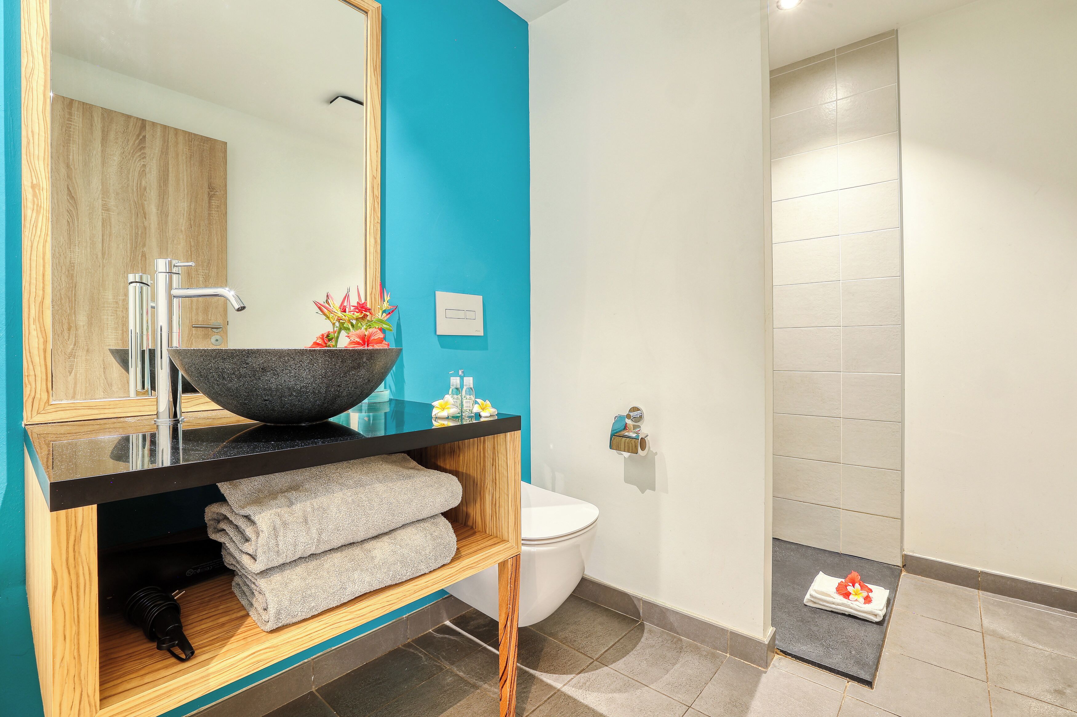 A modern bathroom with a large mirror, a vessel sink, and a toilet.