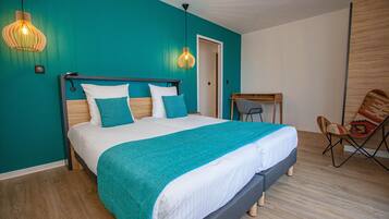 Un dormitorio moderno con una pared verde azulado, una cama grande con cabecera de madera, un escritorio pequeño y una silla colorida.