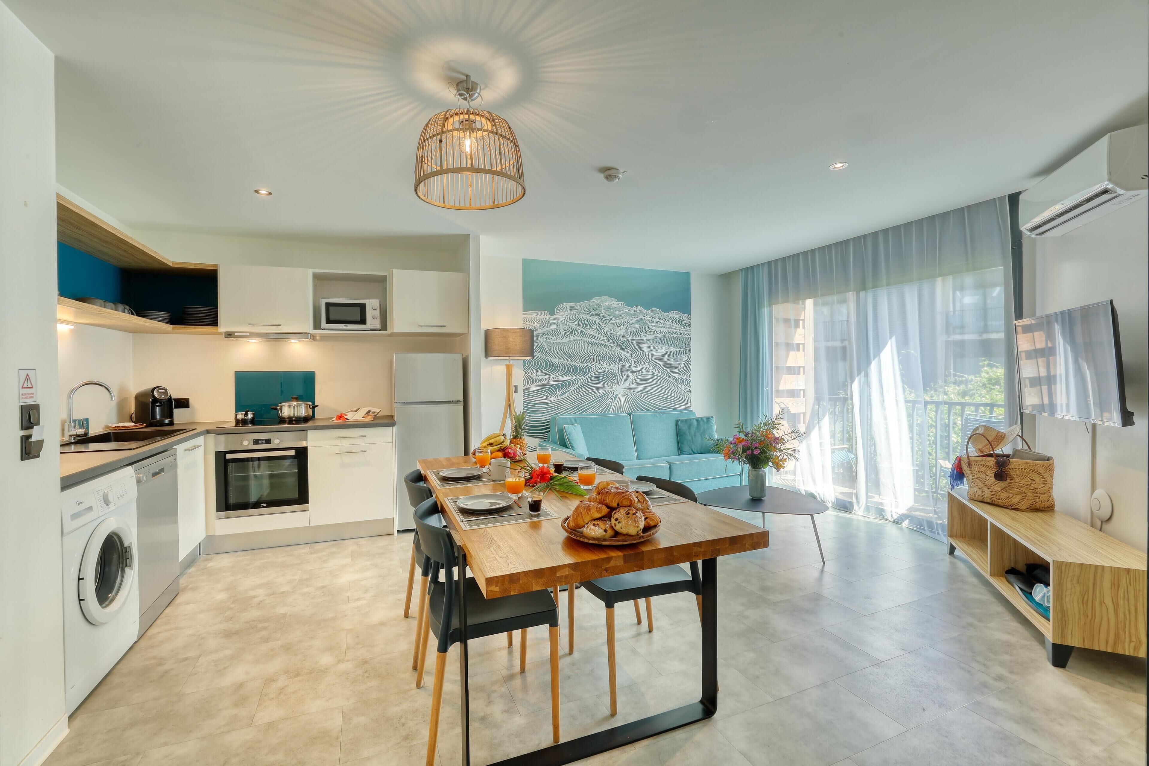 Una cocina moderna con comedor, un ventanal con cortinas y un televisor de pantalla plana.