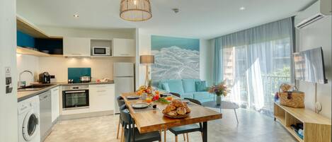 Una cocina moderna con comedor, un ventanal con cortinas y un televisor de pantalla plana.