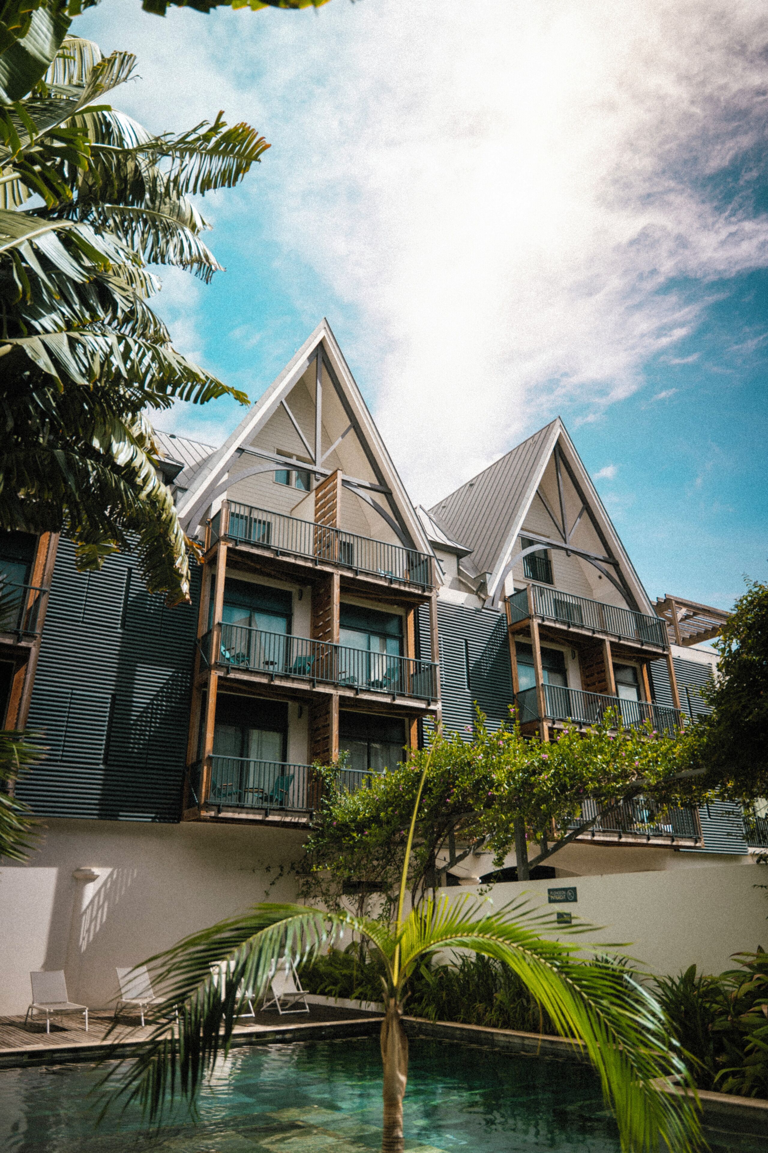 Um hotel com várias varandas, piscina e vegetação exuberante.