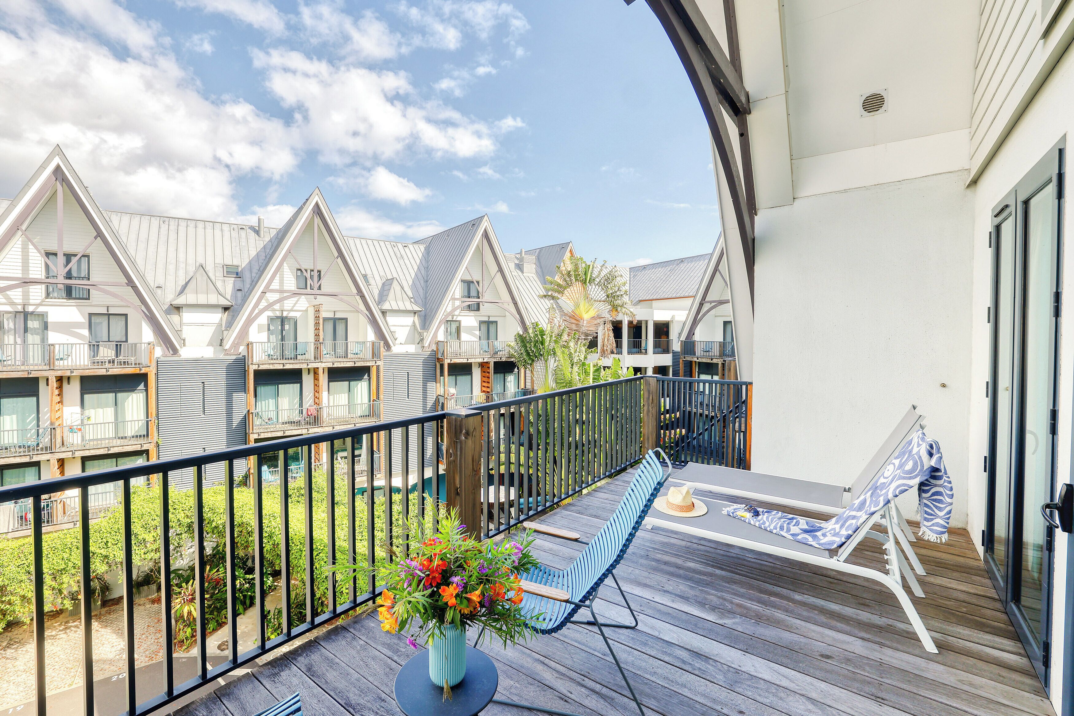 A balcony with a blue chair and a potted plant.