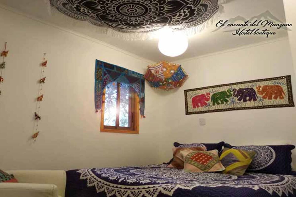 Una habitación con una cama, un ventanal con vistas coloridas, un tapiz en la pared y un diseño en el techo.