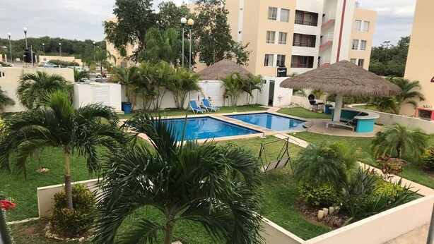 Ein Swimmingpool, umgeben von Palmen und einem Gebäude mit Balkonen.