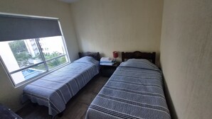 Ein Zimmer mit zwei Betten, einem Fenster und einem Nachttisch mit Lampe.