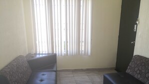 Ein Wohnzimmer mit zwei Sofas, gefliestem Boden und einer Tür.