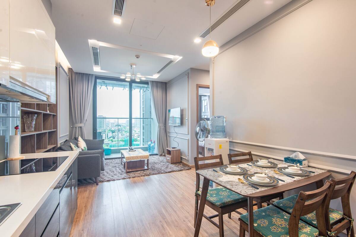 Un salon moderne avec un coin repas, de grandes fenêtres et une vue sur la ville.