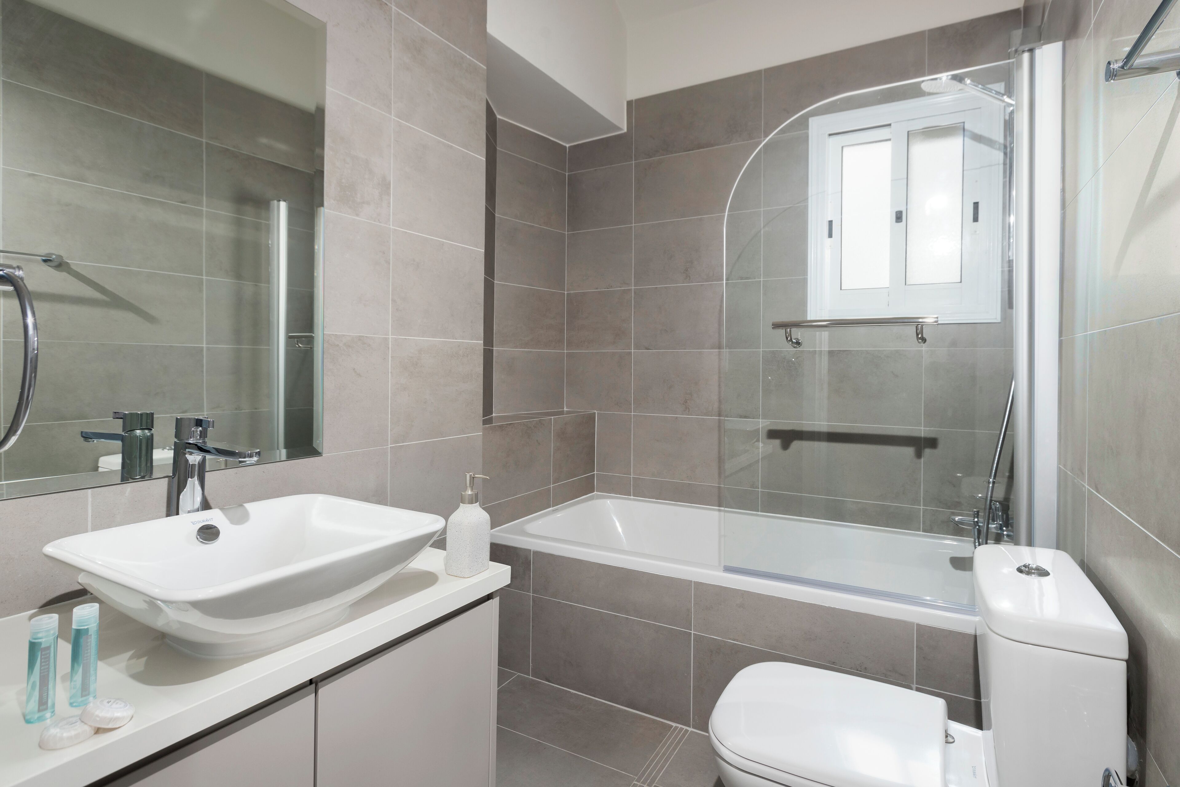 Um banheiro moderno com pia branca, banheira e vaso sanitário.