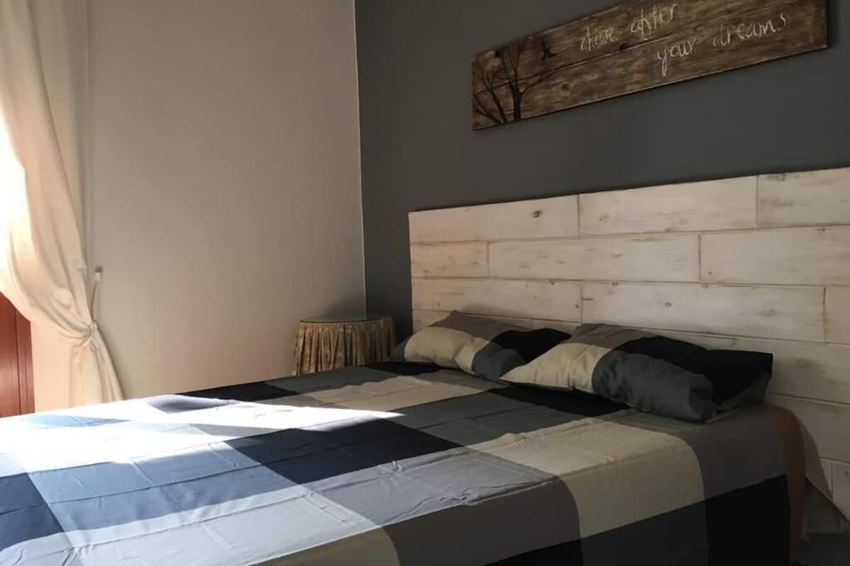 A bedroom with a wooden headboard, a quilted bedspread, and a motivational quote on the wall.