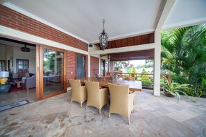 An open-plan living area with a dining table, wicker chairs, and a view of the outdoors. - ☀Sunset☀ Beachfront Dreamvilla Lovina with pool (Lovina)