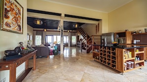 A spacious living area with a wooden coffee table, a sofa, a kitchen area with a refrigerator and microwave, and a staircase leading to another level. - ☀Sunset☀ Beachfront Dreamvilla Lovina with pool (Lovina)