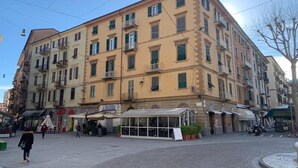 En byggnad med flera våningar, balkonger och ett café på markplan.