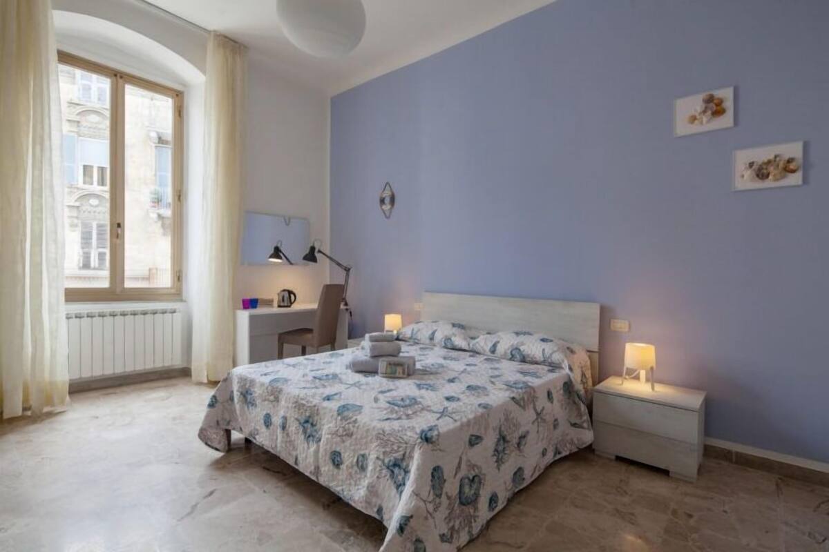 Een slaapkamer met een bed, nachtkastjes, een bureau en een raam.