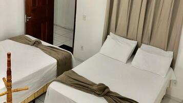 A hotel room with two single beds, a wooden door, an air conditioning unit, and a mirror.