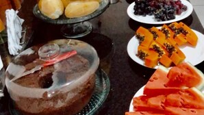 Une table de buffet proposant divers aliments, notamment du pain, des fruits et un gâteau.