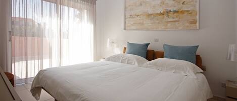 A hotel room with a large bed, two pillows, a nightstand, a lamp, and a large abstract painting on the wall.