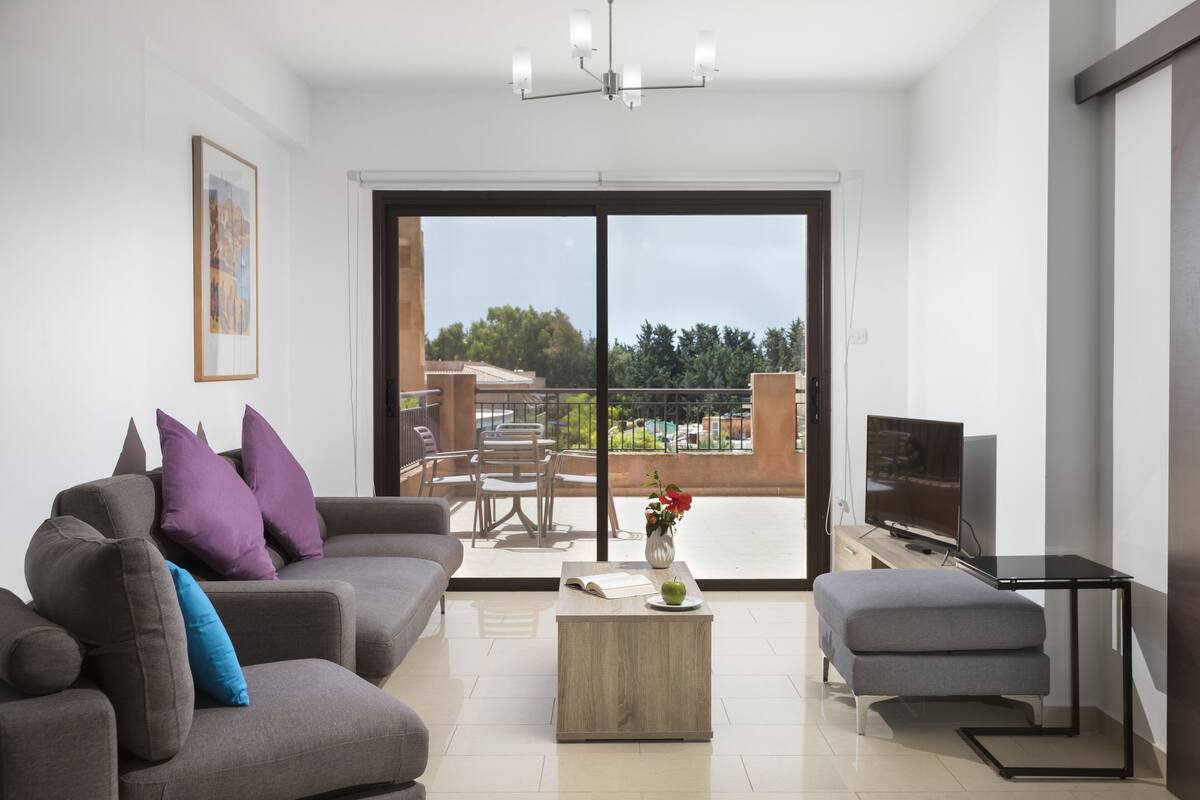 Una sala de estar moderna con un sofá gris, una mesa de centro y un televisor.