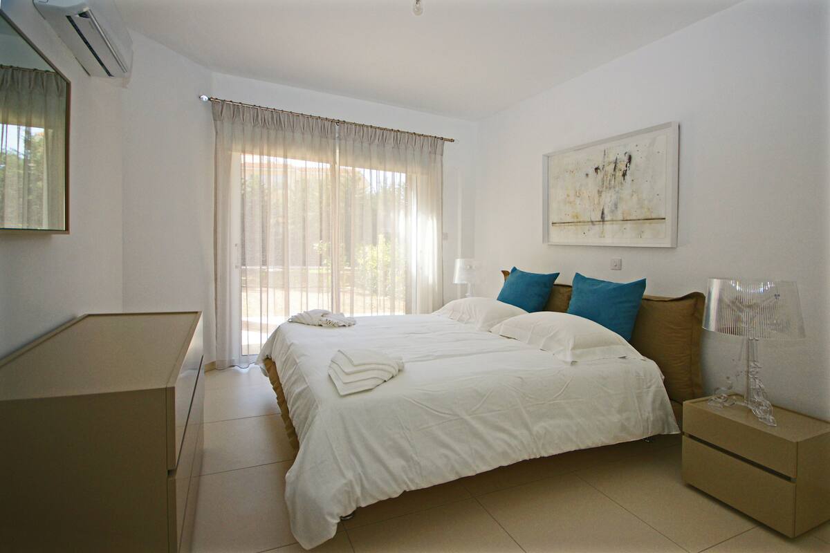 Un dormitorio con una cama grande, una mesita de noche, una lámpara y un cuadro en la pared.