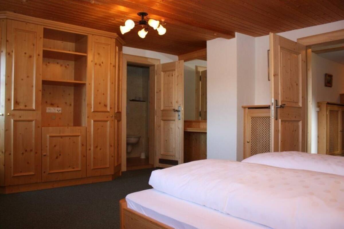 A wooden room with a bed, a wardrobe, and a bathroom.