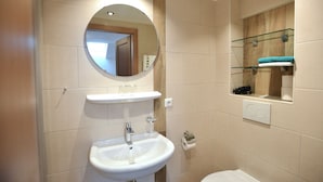 Un baño con un espejo redondo, un lavabo y un inodoro.